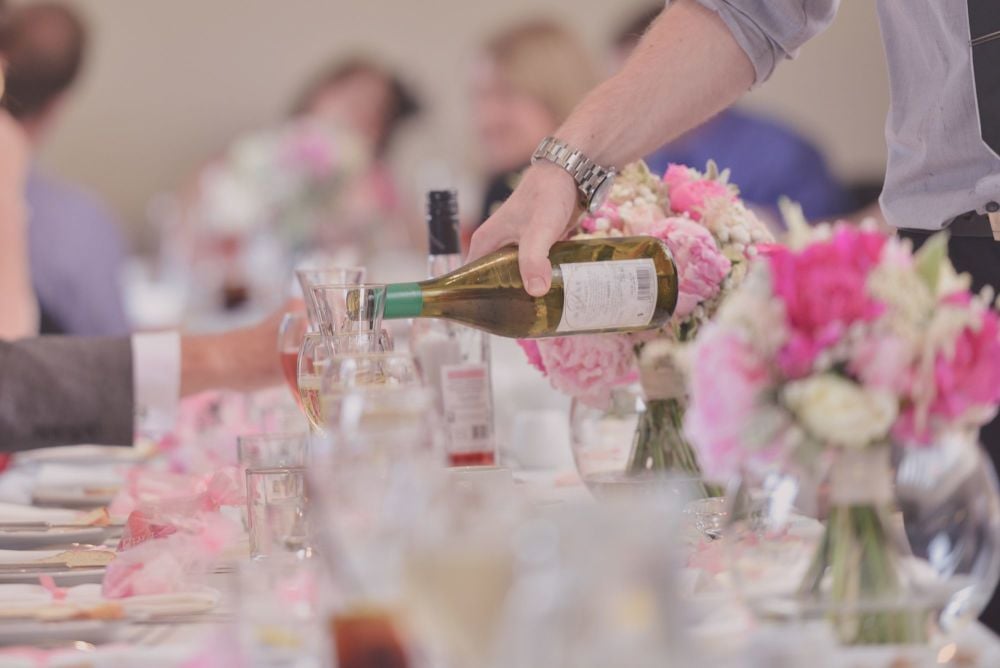 Man Pouring Wine At Wedding Restaurant Table