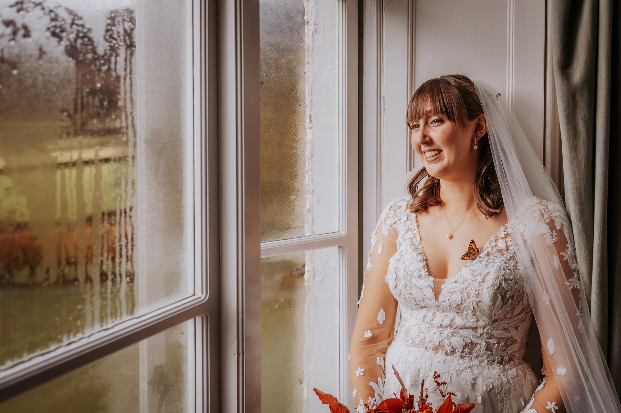 Butterfly resting on the brideâ€™s lace wedding dress during bridal prep at Lancrigg in the Lake District.