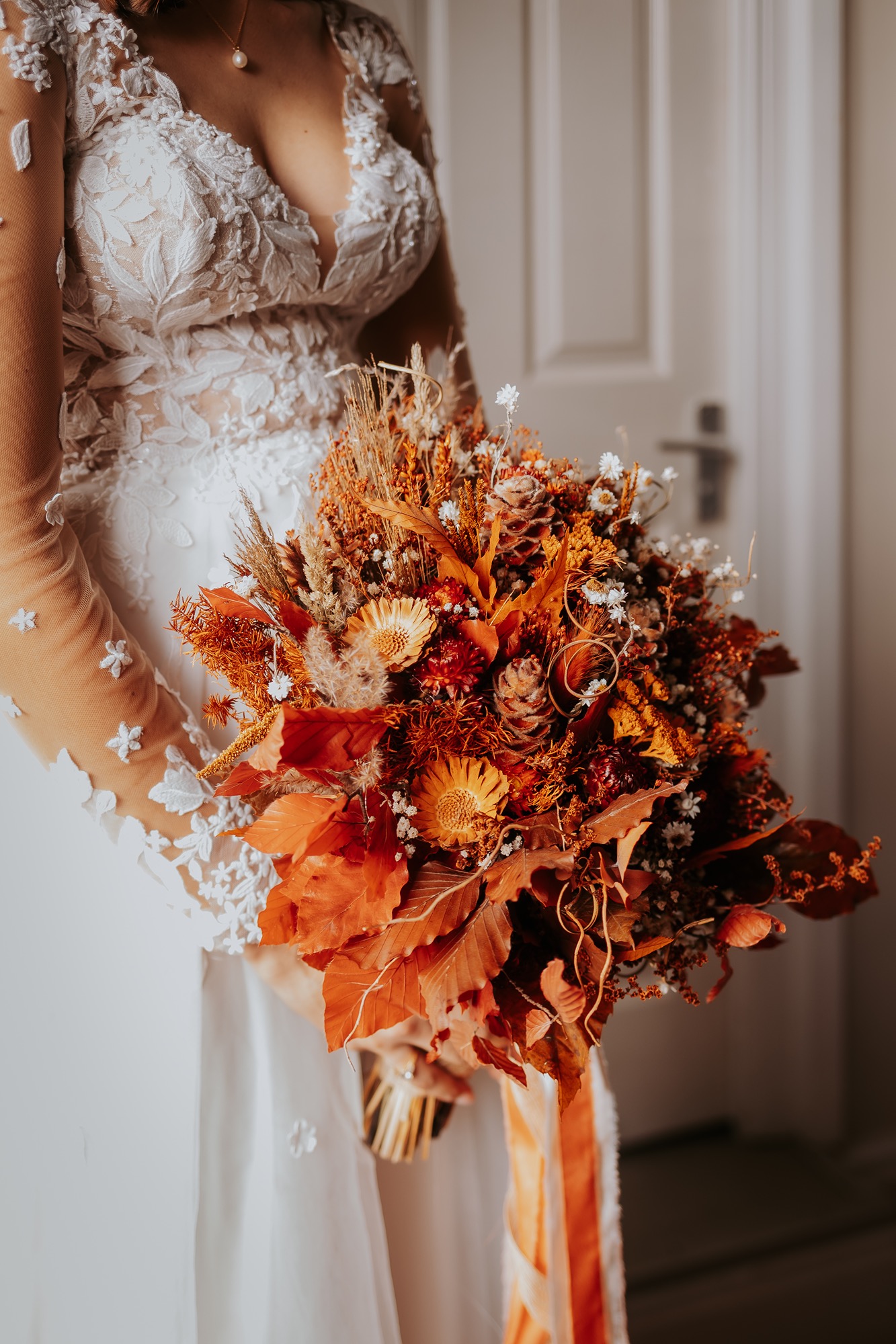 Close-up of the brideâ€™s autumnal bouquet featuring dried flowers, pinecones, and rust-coloured foliage.