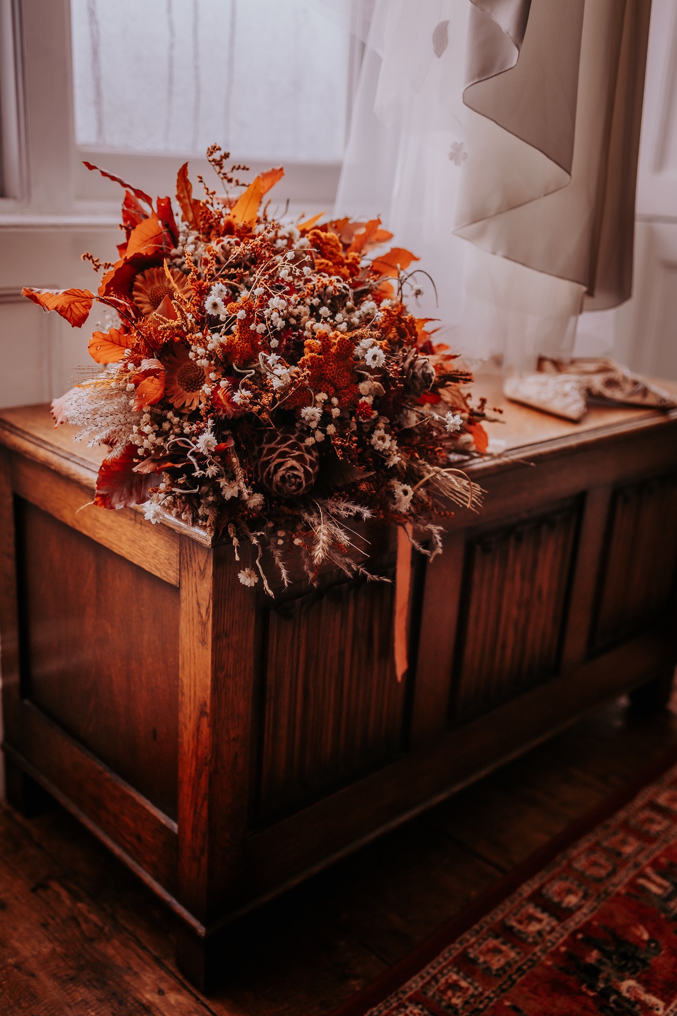 Close-up of the brideâ€™s autumnal bouquet featuring dried flowers, pinecones, and rust-coloured foliage.