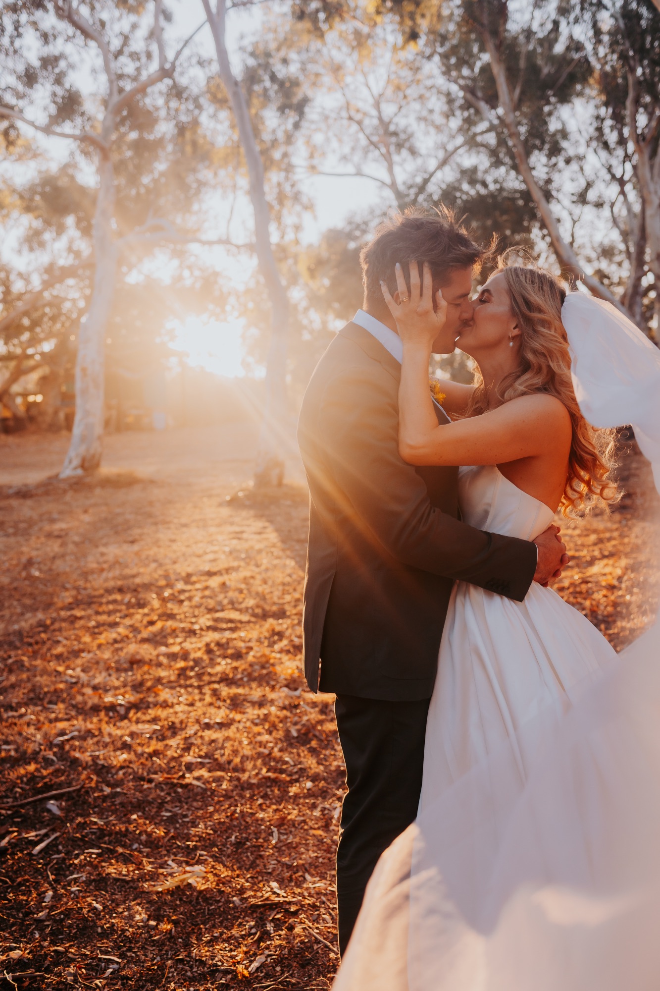 Destination wedding, Nukara Farm, Western Australia, warm wedding, bride and groom kissing with low sun through the trees