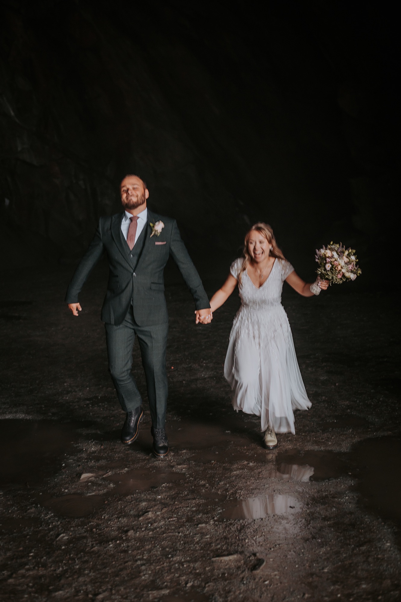 Bride and Groom run through puddles at Rydal caves
