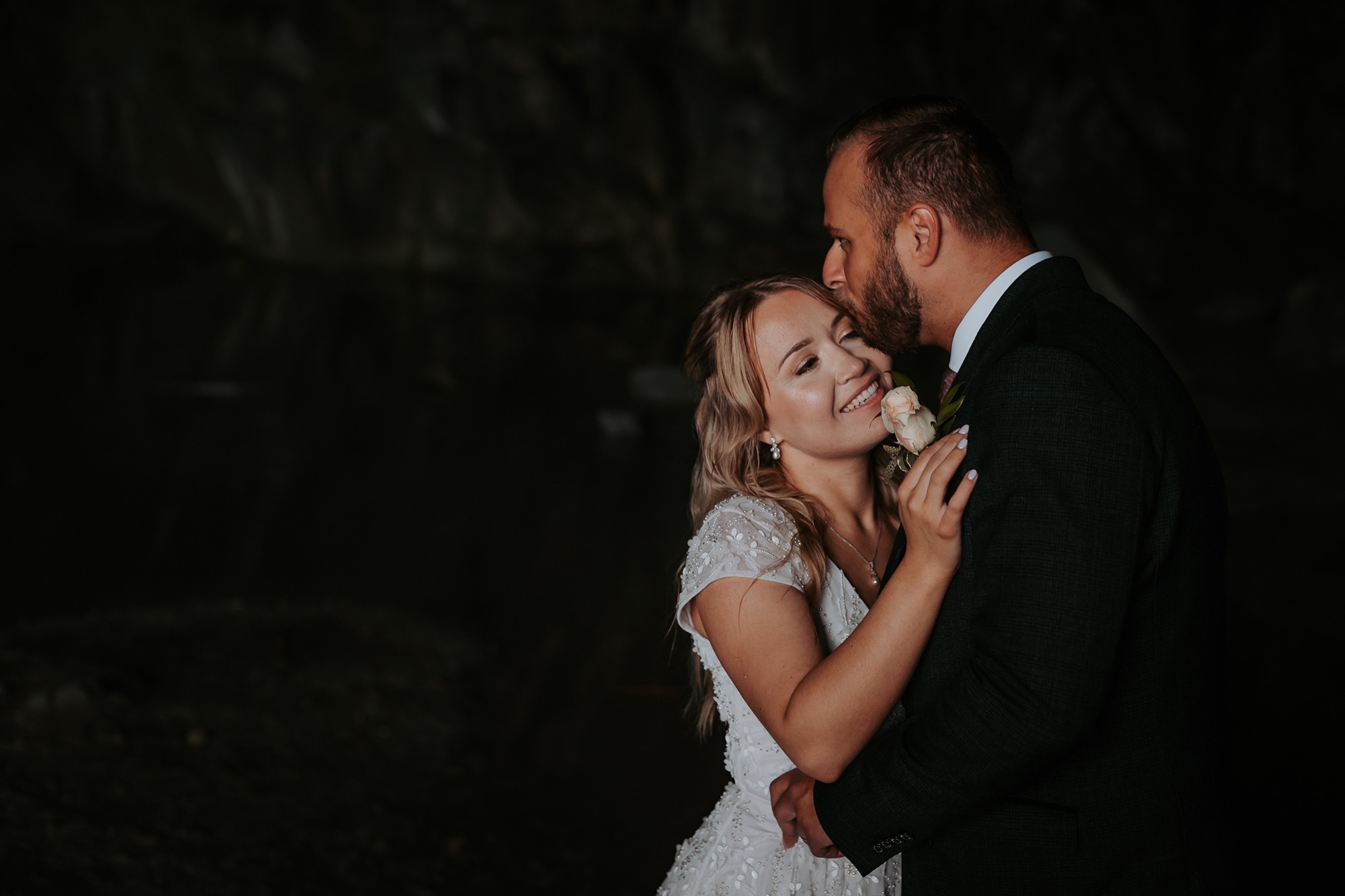 Groom kisses bride on temple in Rydal Caves after being married at Cote How
