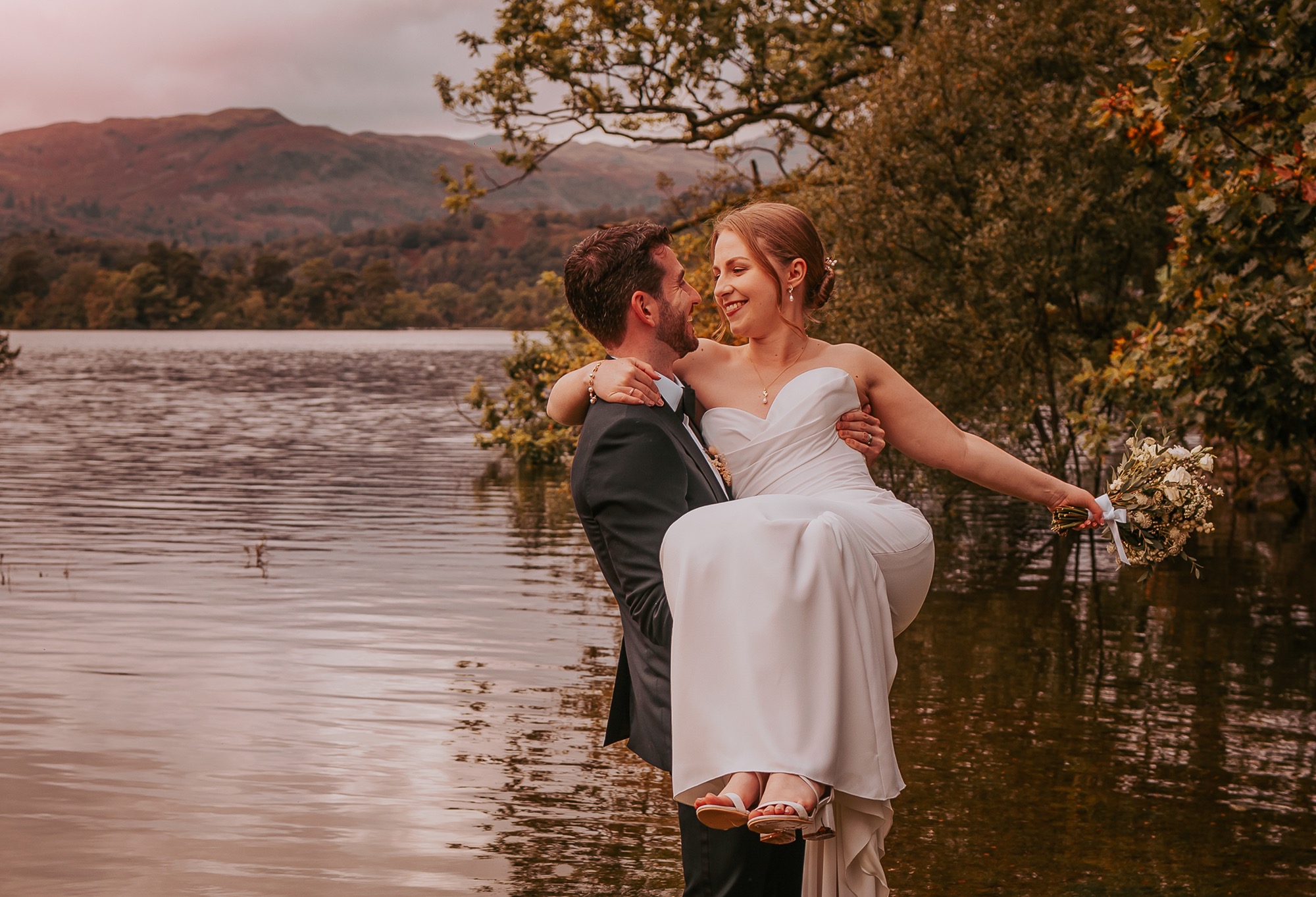 Groom lifting bride at the edge of Rydal water after a Cote How Elopement