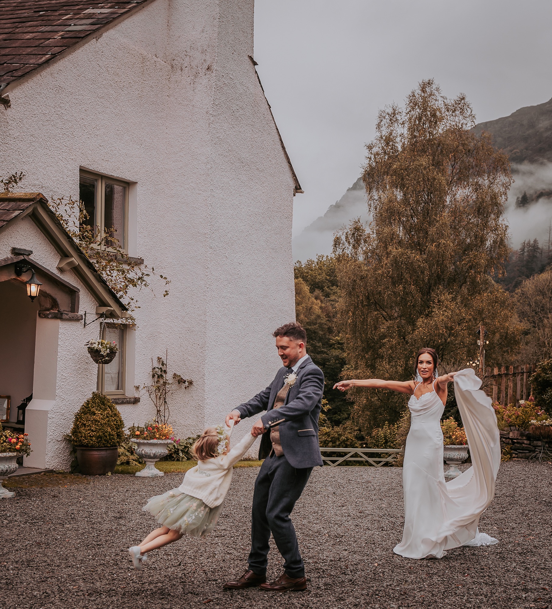 Groom spinning flower girl around as bride dances in the background at Cote How