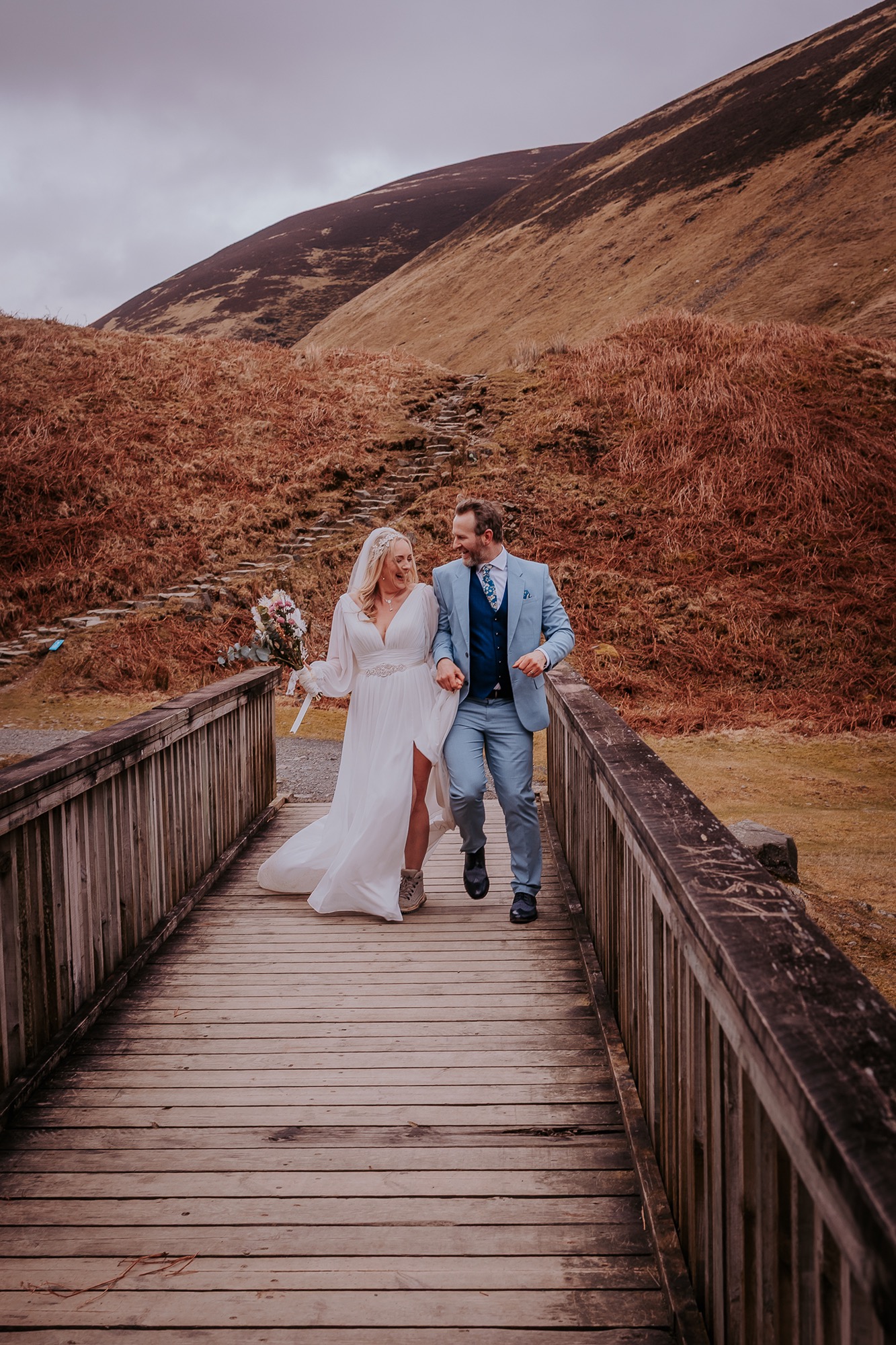 wedding couple walk over country bridge