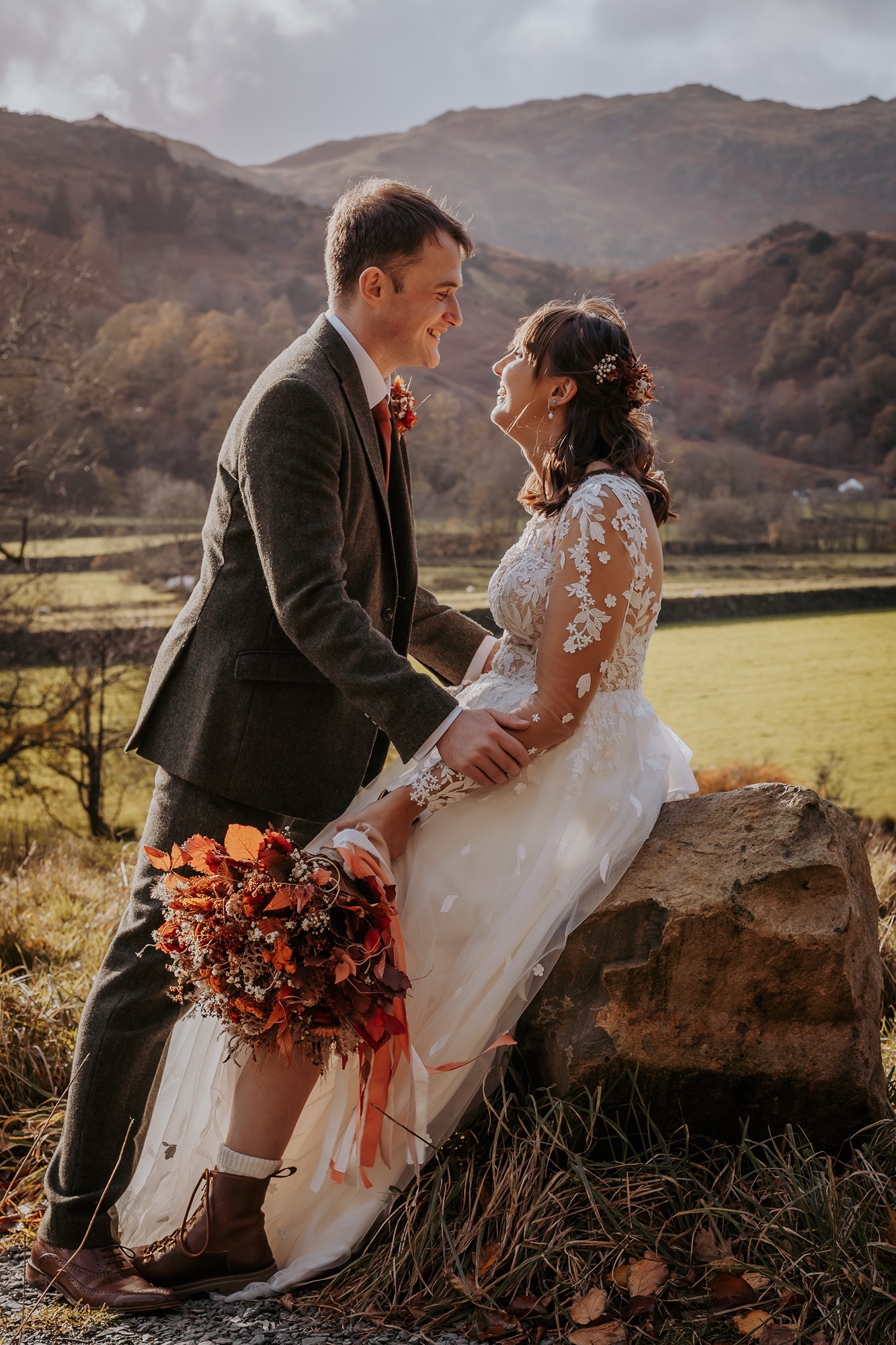 Bride and groom having a quiet moment on a rock whilst taking in the scenery of the Lake District mountains in the distance