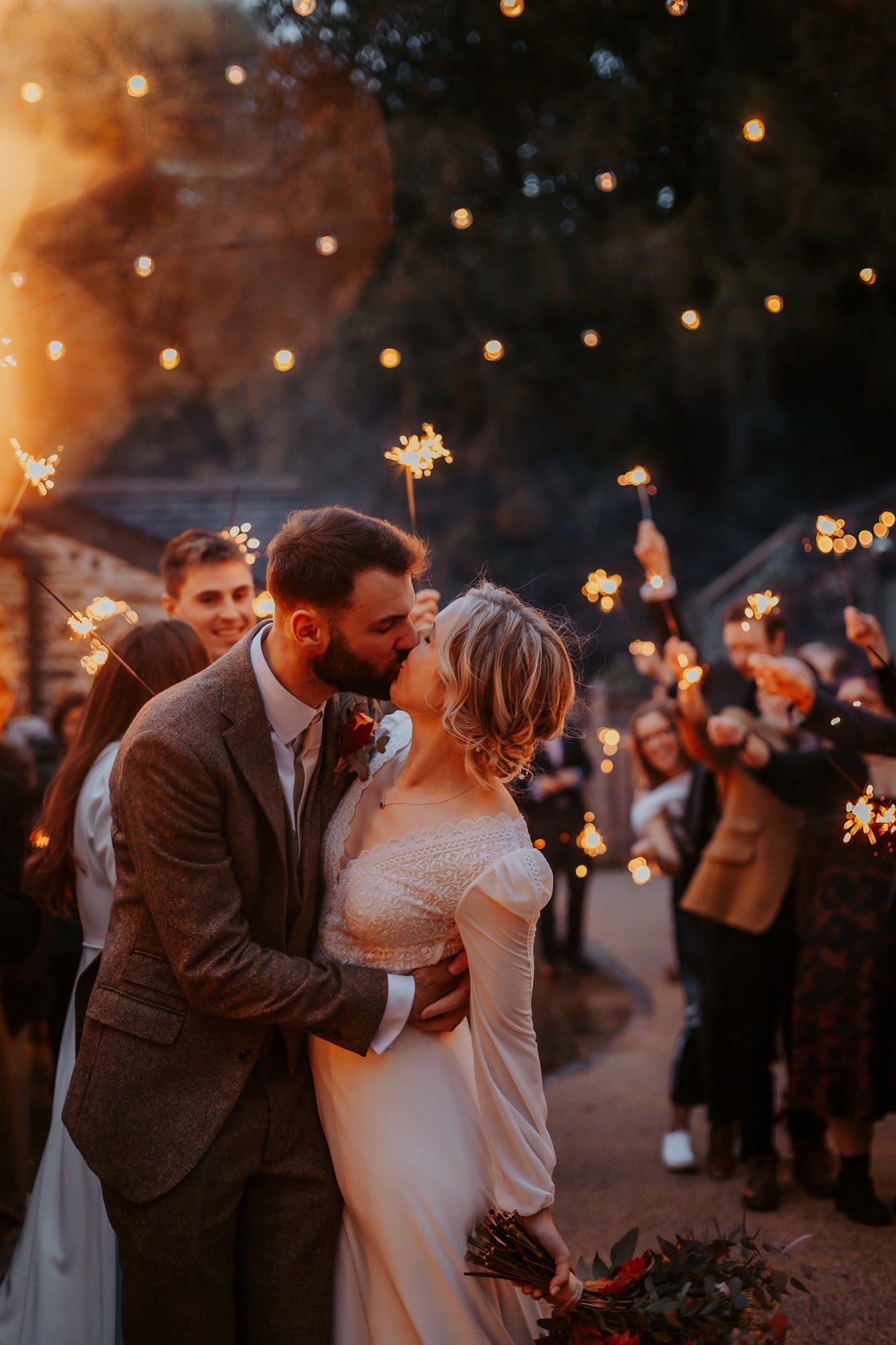 Bride and groom kissing under sparkler arch in Town Head Estate courtyard