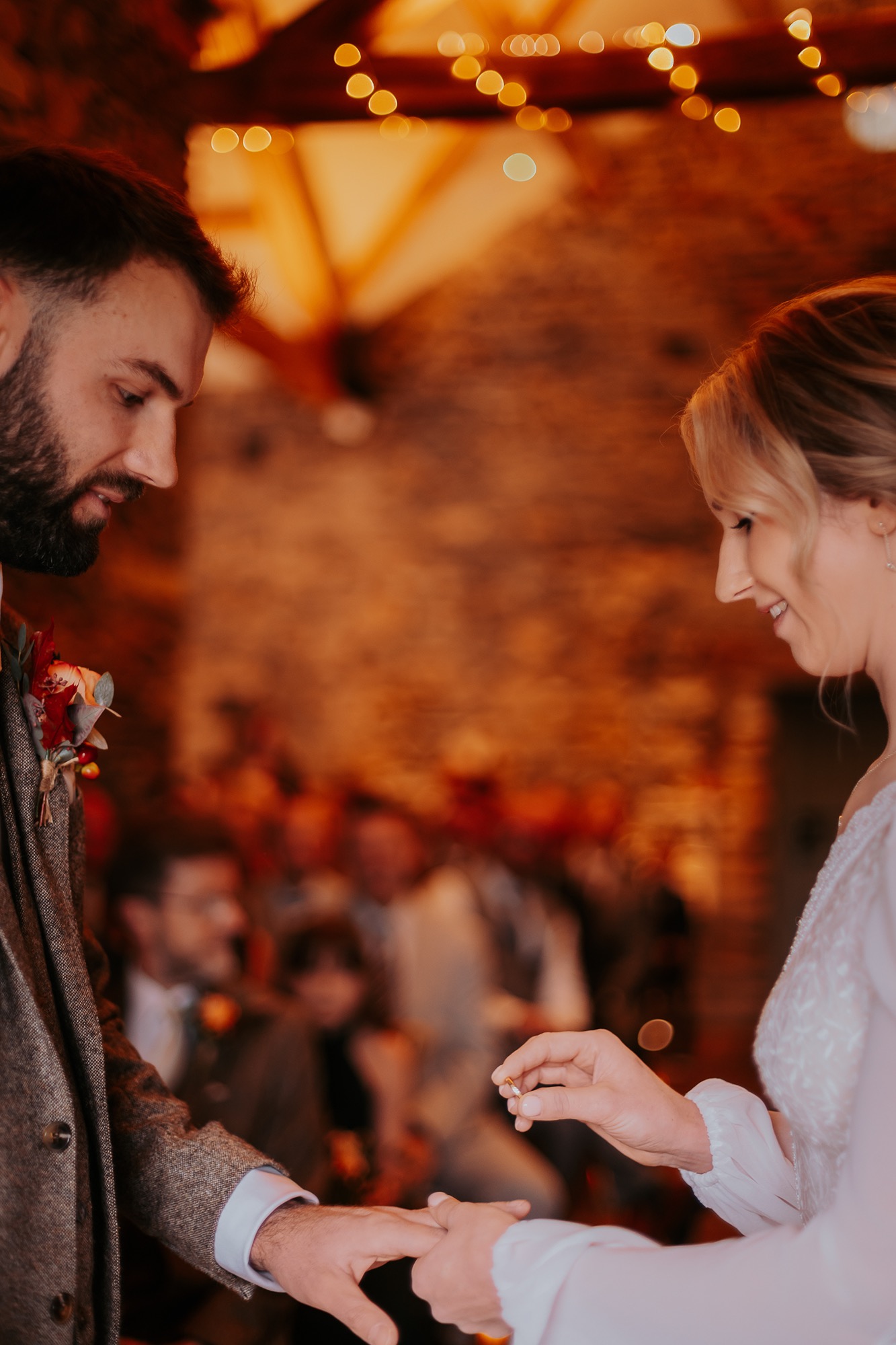 Bride exchanging wedding ring with her groom in Town Head Estates cosy wedding barn