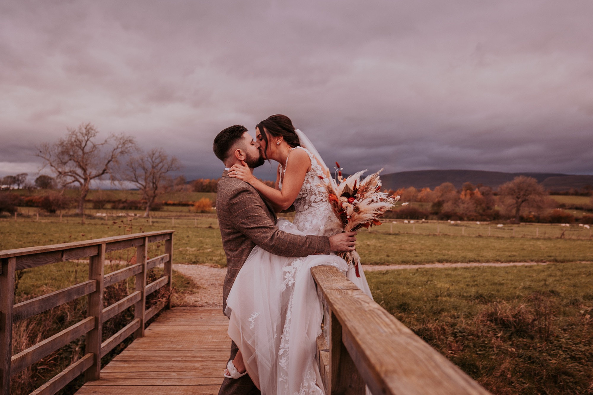 Bride and groom kiss in countryside setting Eden Barn