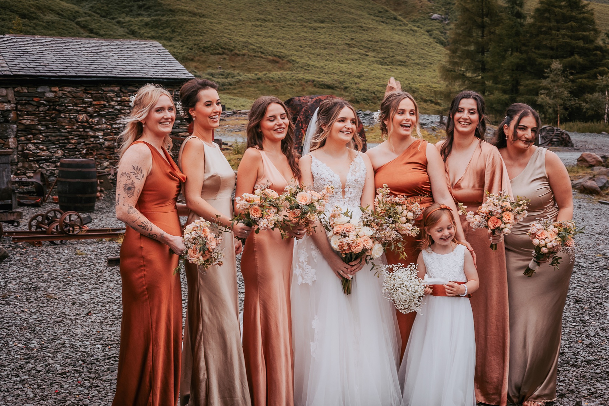 Informal group portrait of bridesmaids in a range of rust colour dresses