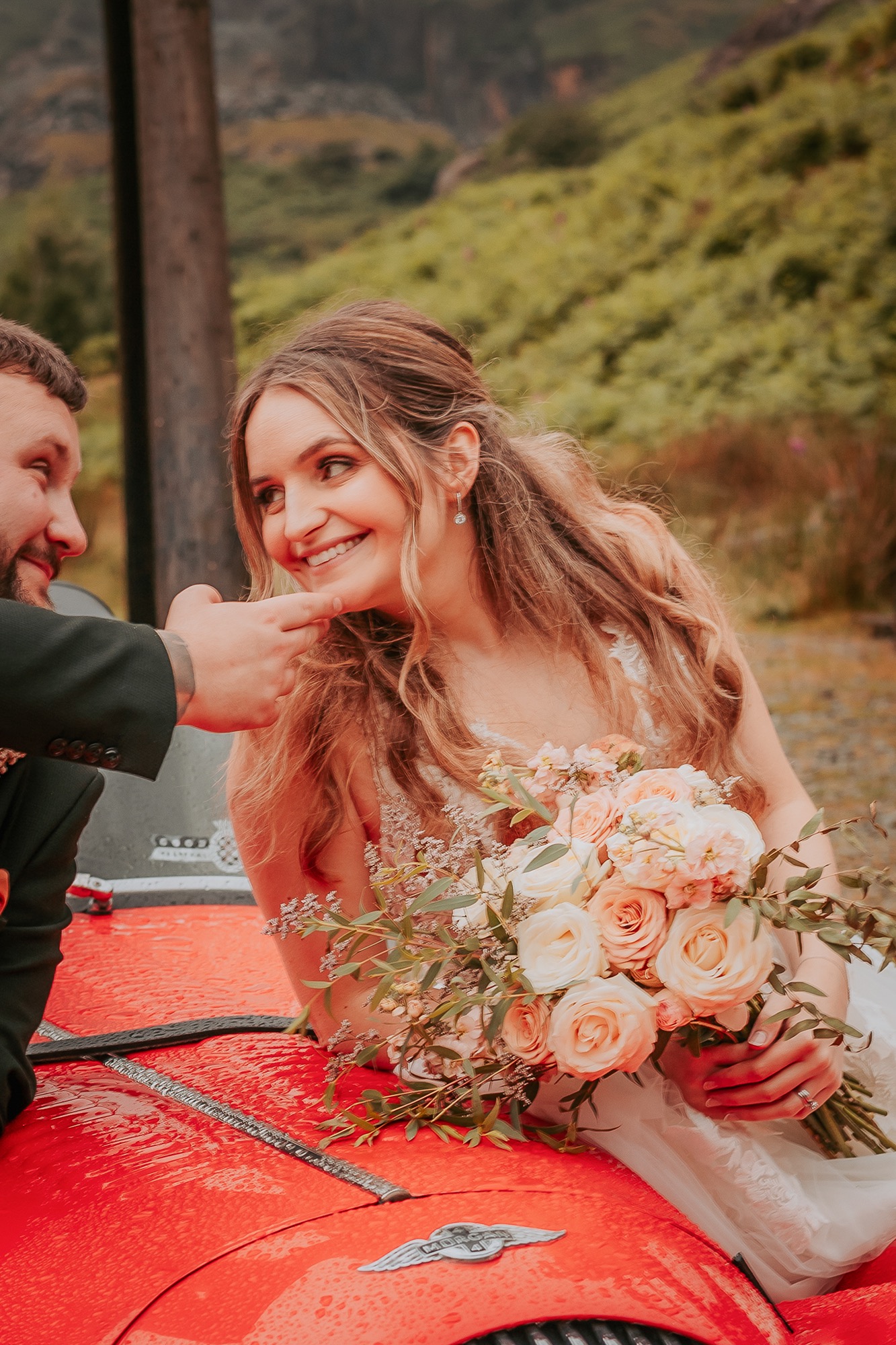Newly-weds look lovingly into each others eyes over vintage car bonnet