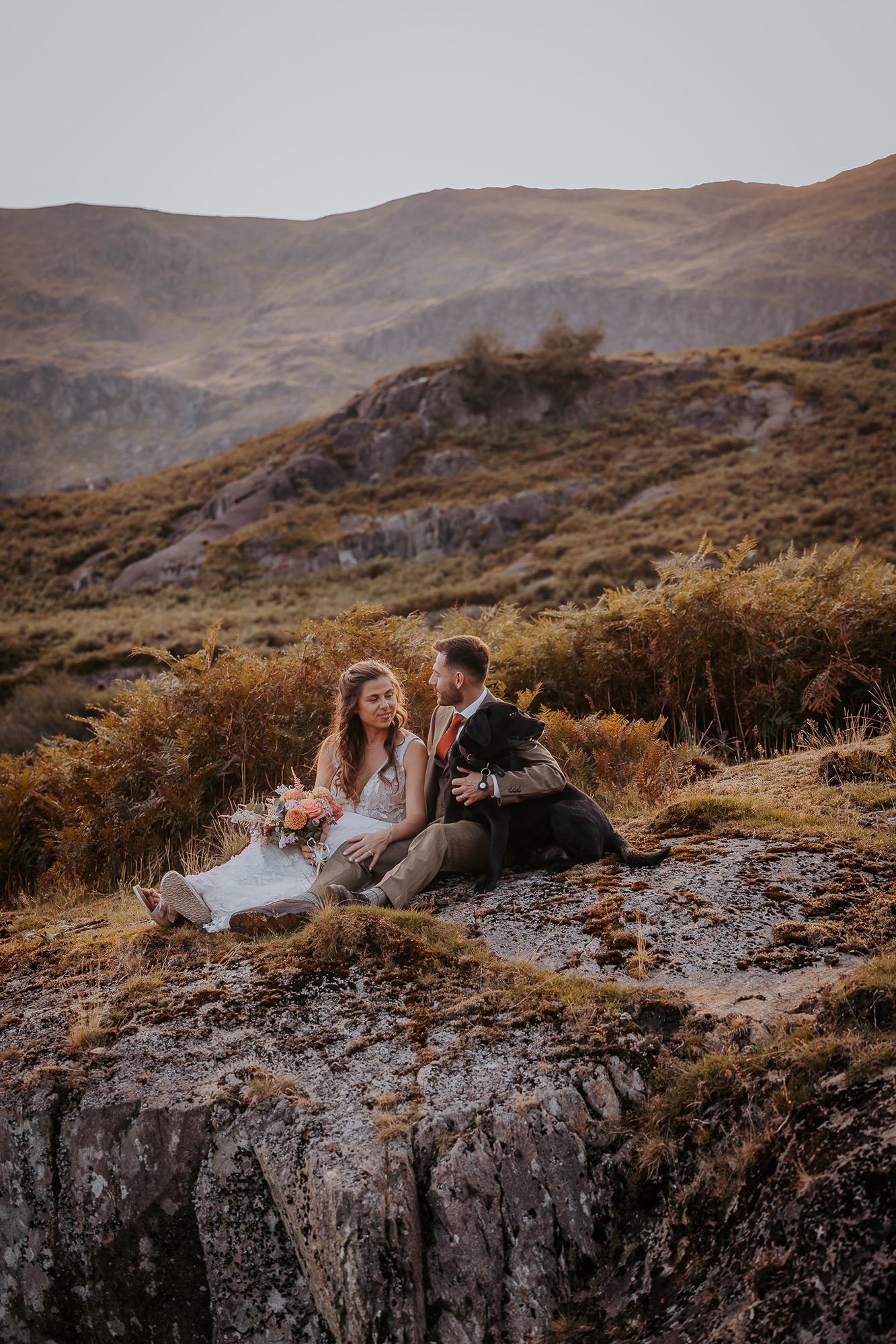 Newly-weds cuddle dog while on the side of Lake District Wainwright