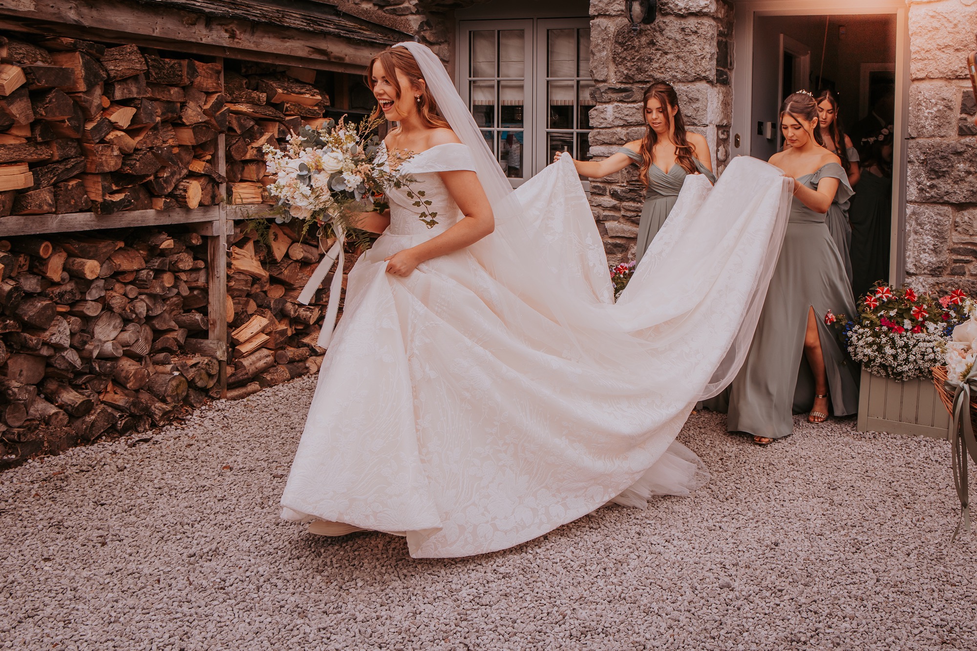 bridesmaid assists bride with large wedding dress train