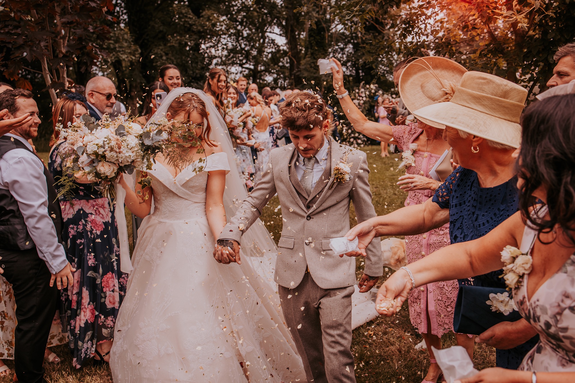 Bride and groom avoid confetti during confetti throwing at farm wedding
