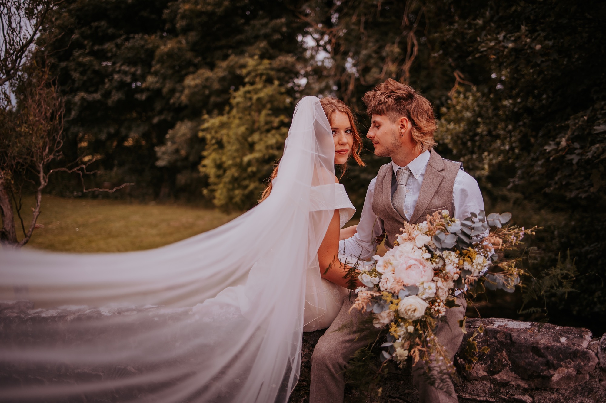 bride and groom sit on bridge and enjoy a quiet moment