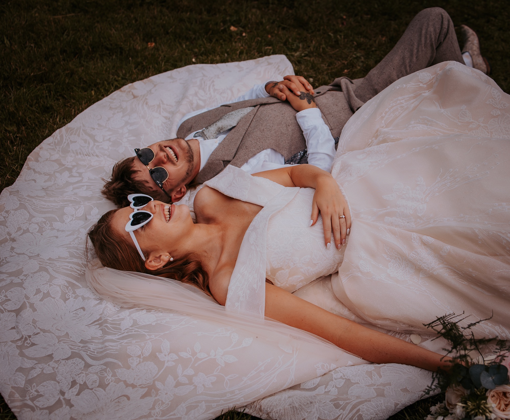 bride and groom lay in sunshine with shades on