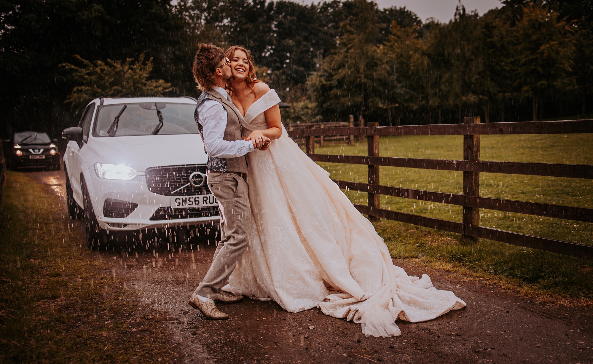 groom kisses bride on cheek whilst they dance in the rain, North Yorkshire wedding