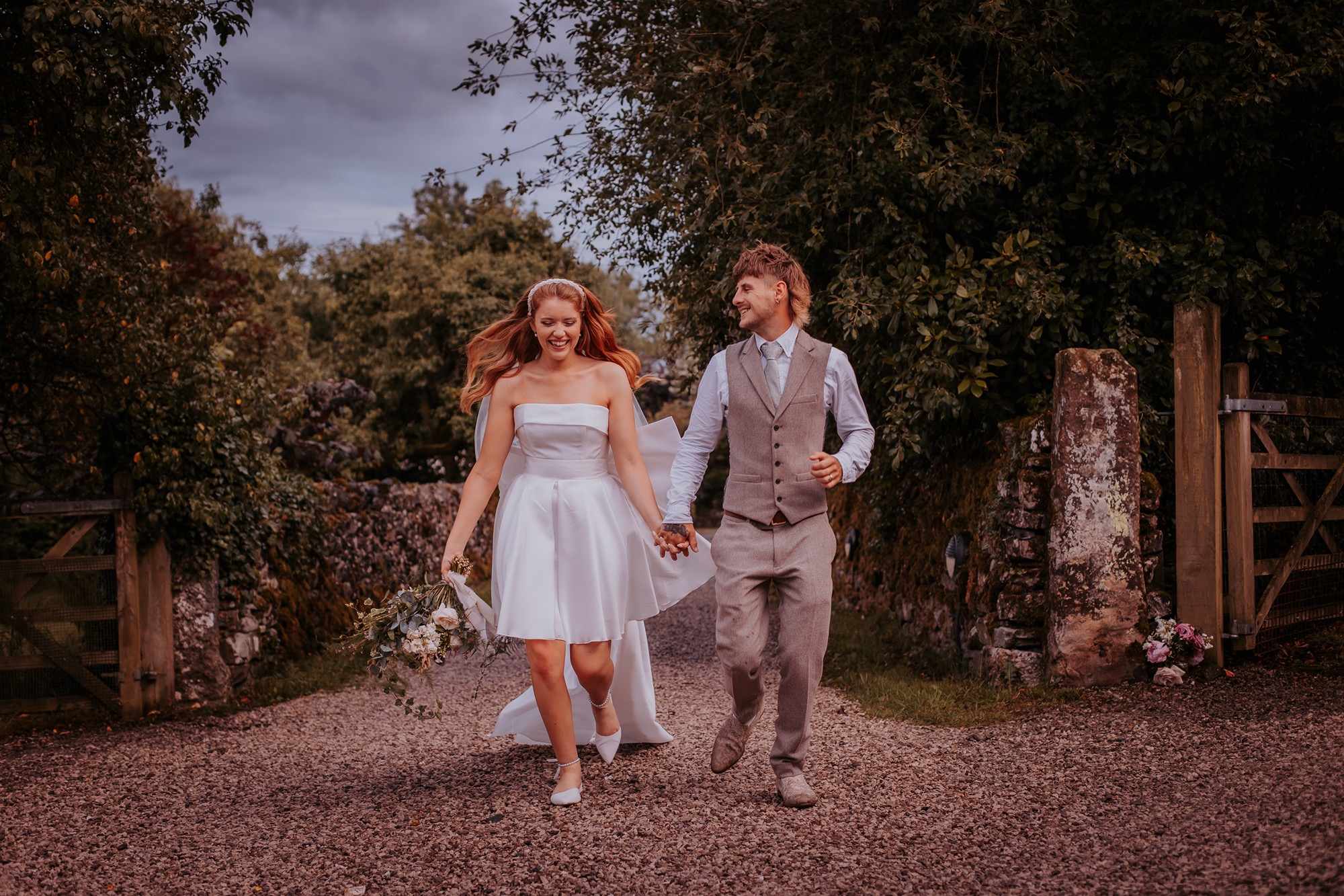 bride and groom run down country lane hand-in-hand