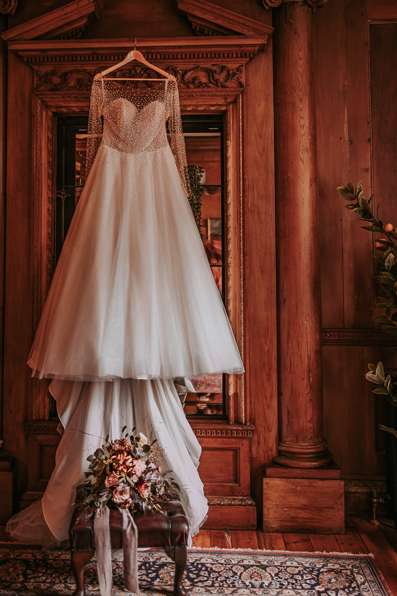 Bridal dress hung in Holefoot bedroom with bridal bouquet on footstool