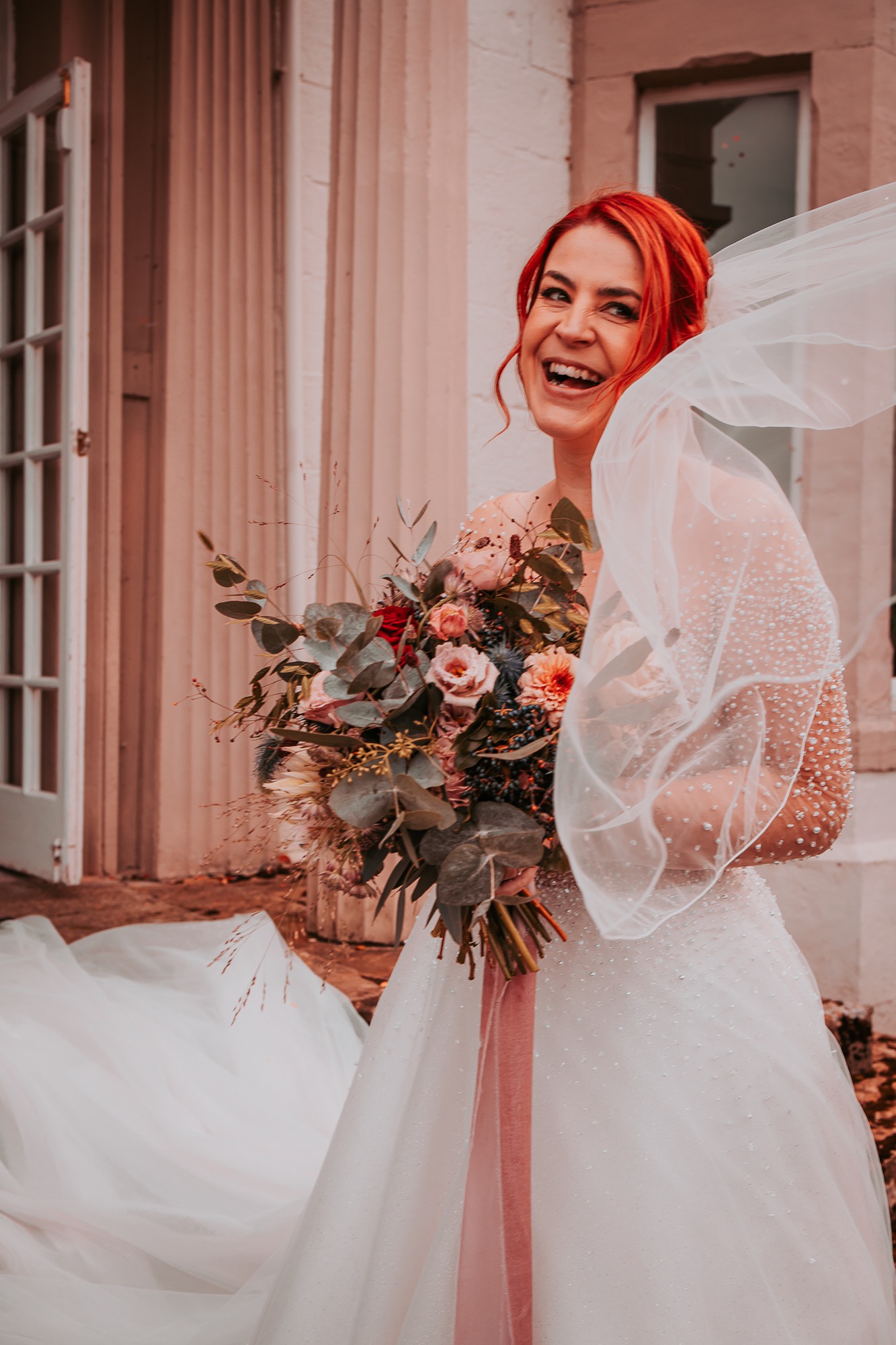 Bride laughing naturally with bridal bouquet outside Holesfoot House, Penrith