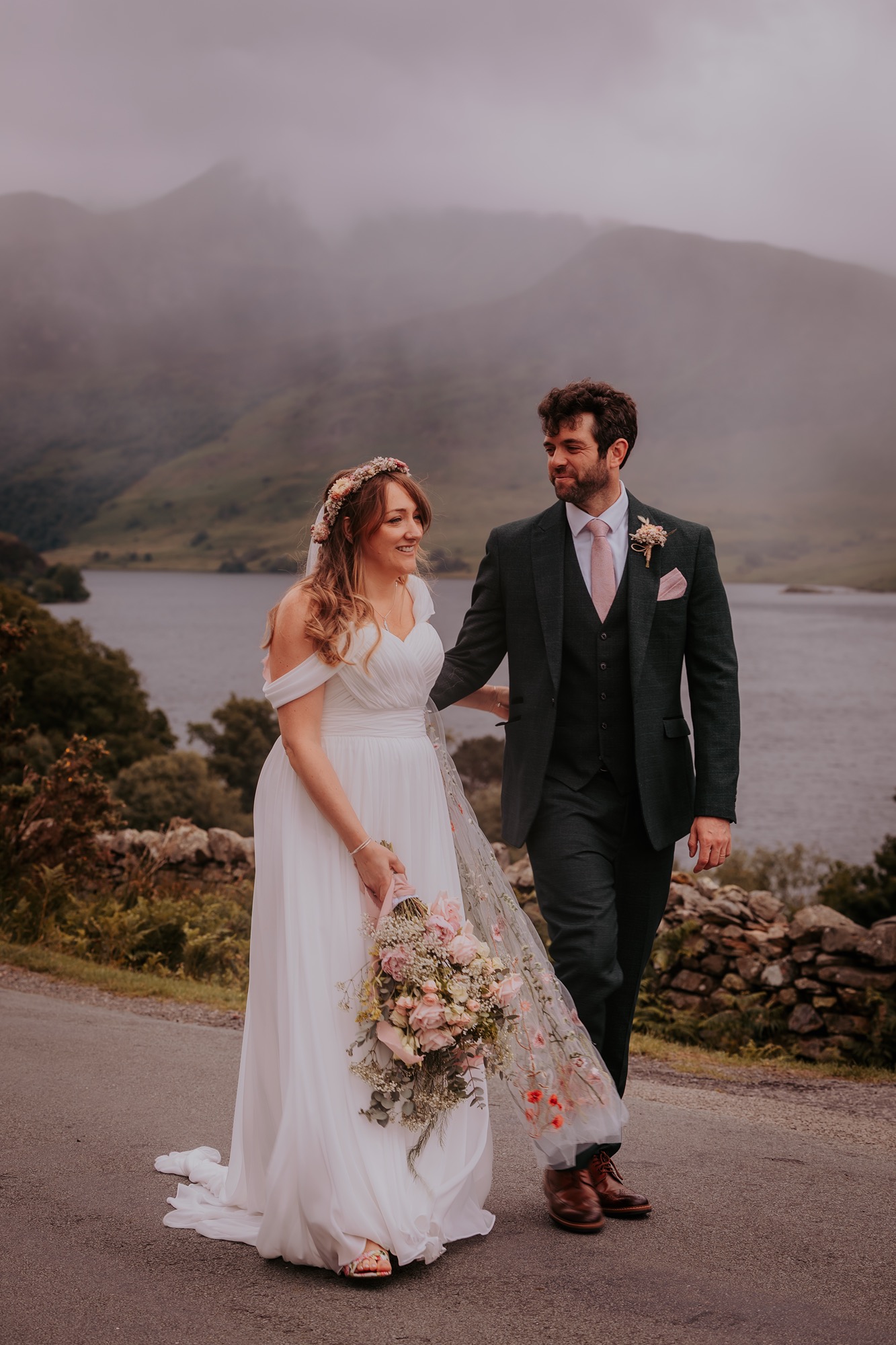 Bride and groom walk at the side of Crummock water, Lake District