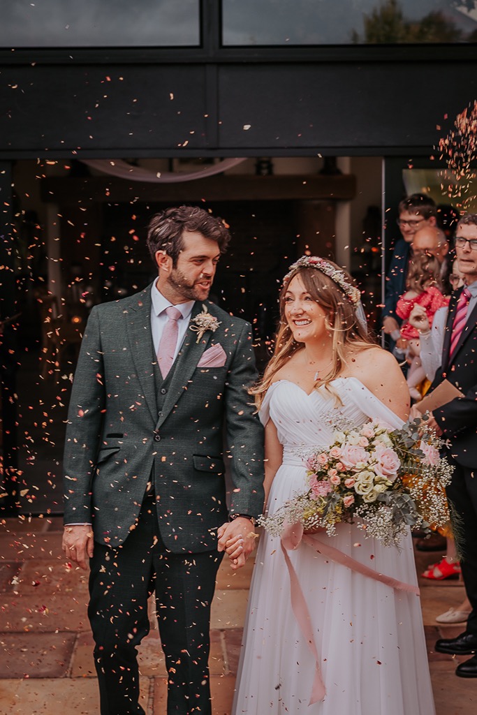 Bridal bouquet popping with fresh pink colours as couple walk through confetti at New House Farm, Cumbria