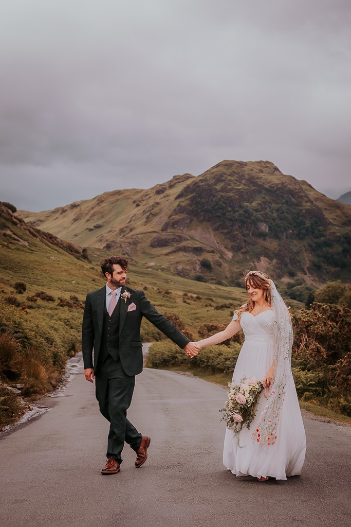 bride and groom dance in the road near Crummock water, The Lake District