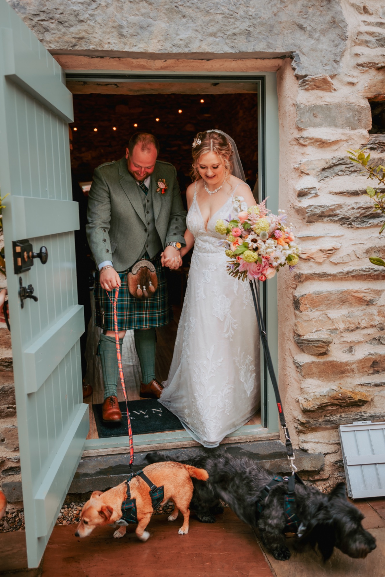 Bride and groom exit Town Head Estates wedding barn with their dogs