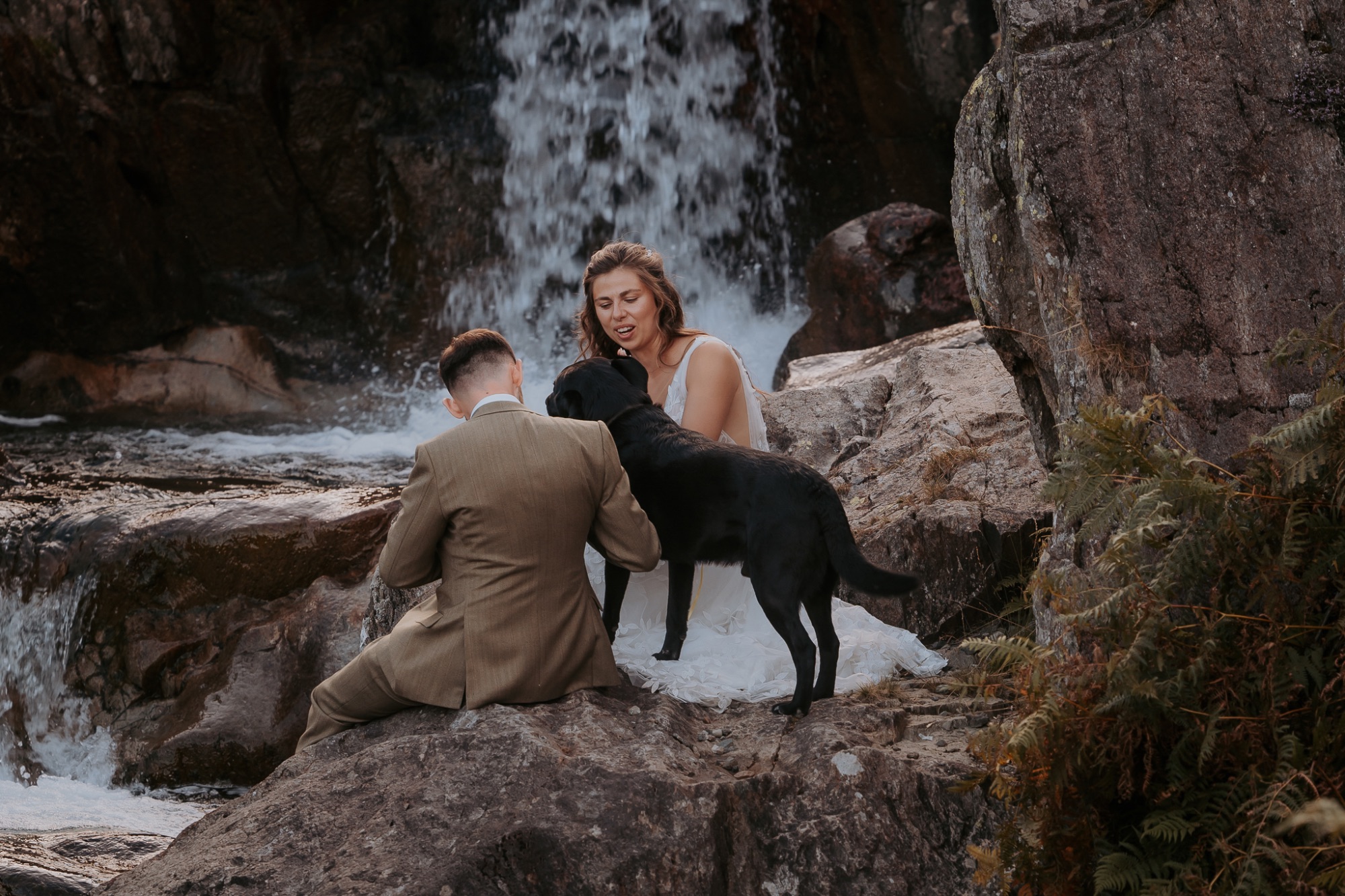 Bride and groom chat to their dog at the waterfalls edge, Coniston Coppermines