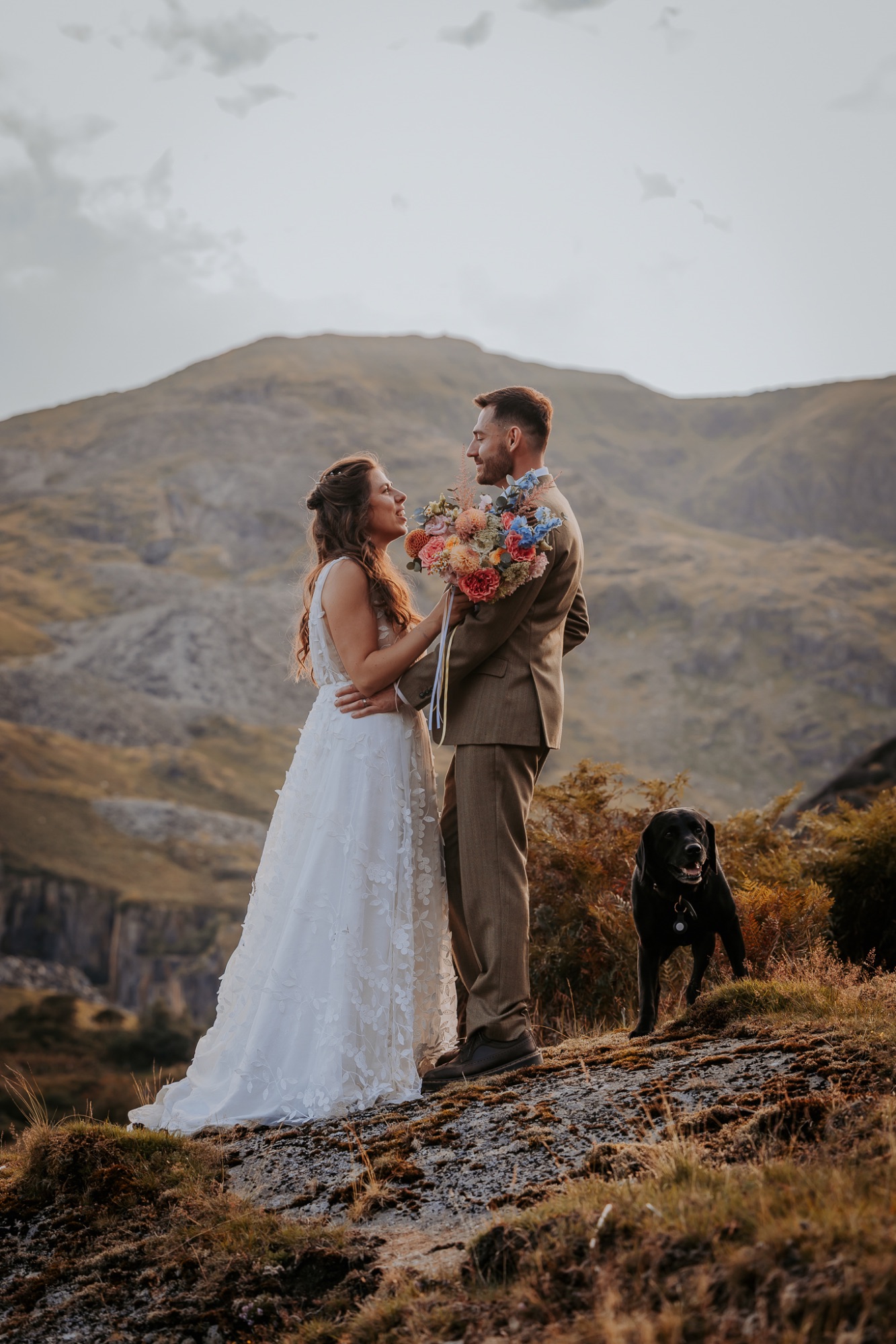 Newly-wed couple enjoy a moment on the mountainside with their dog 