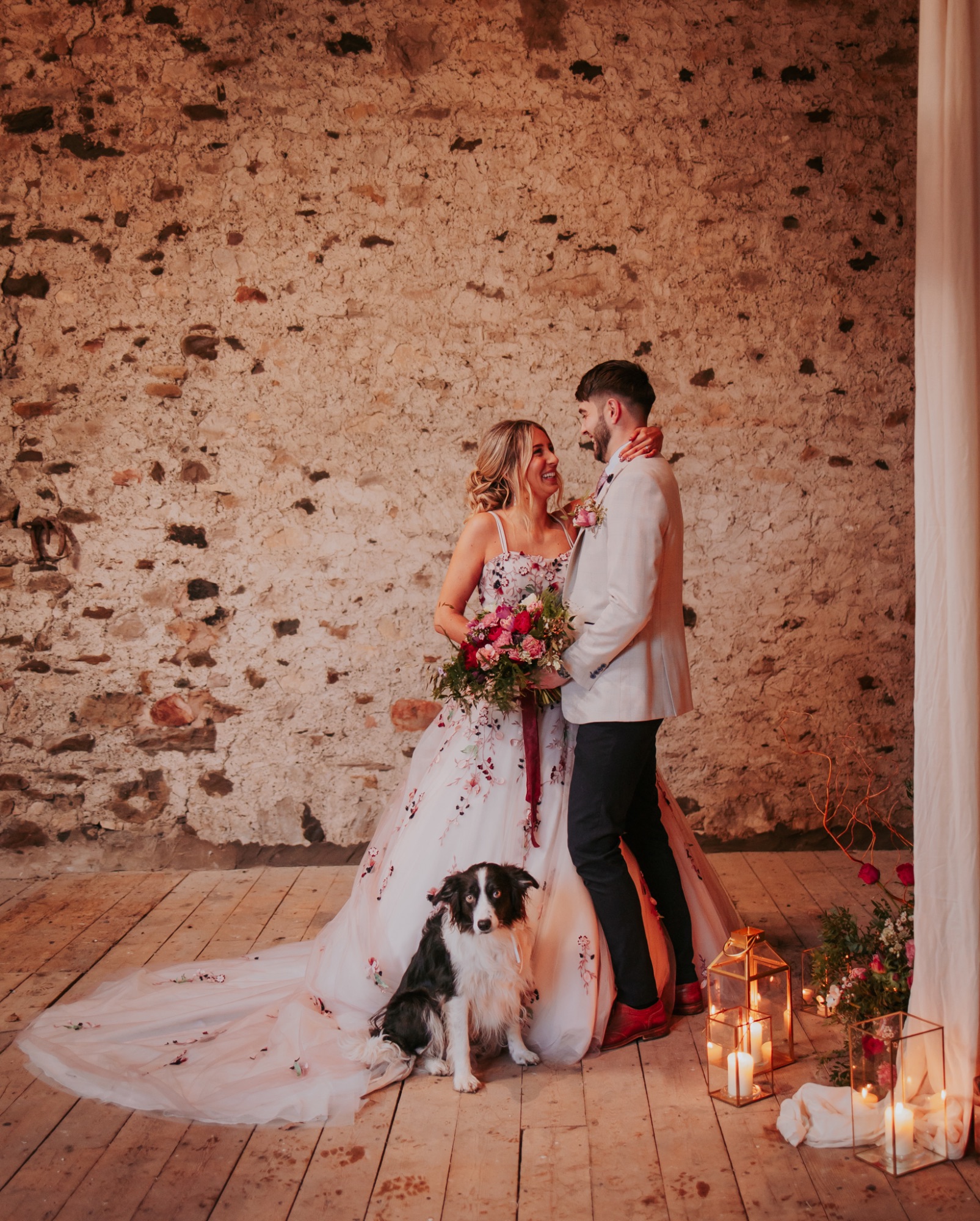 Newly-wed couple embrace each other as their dog sits at their feet