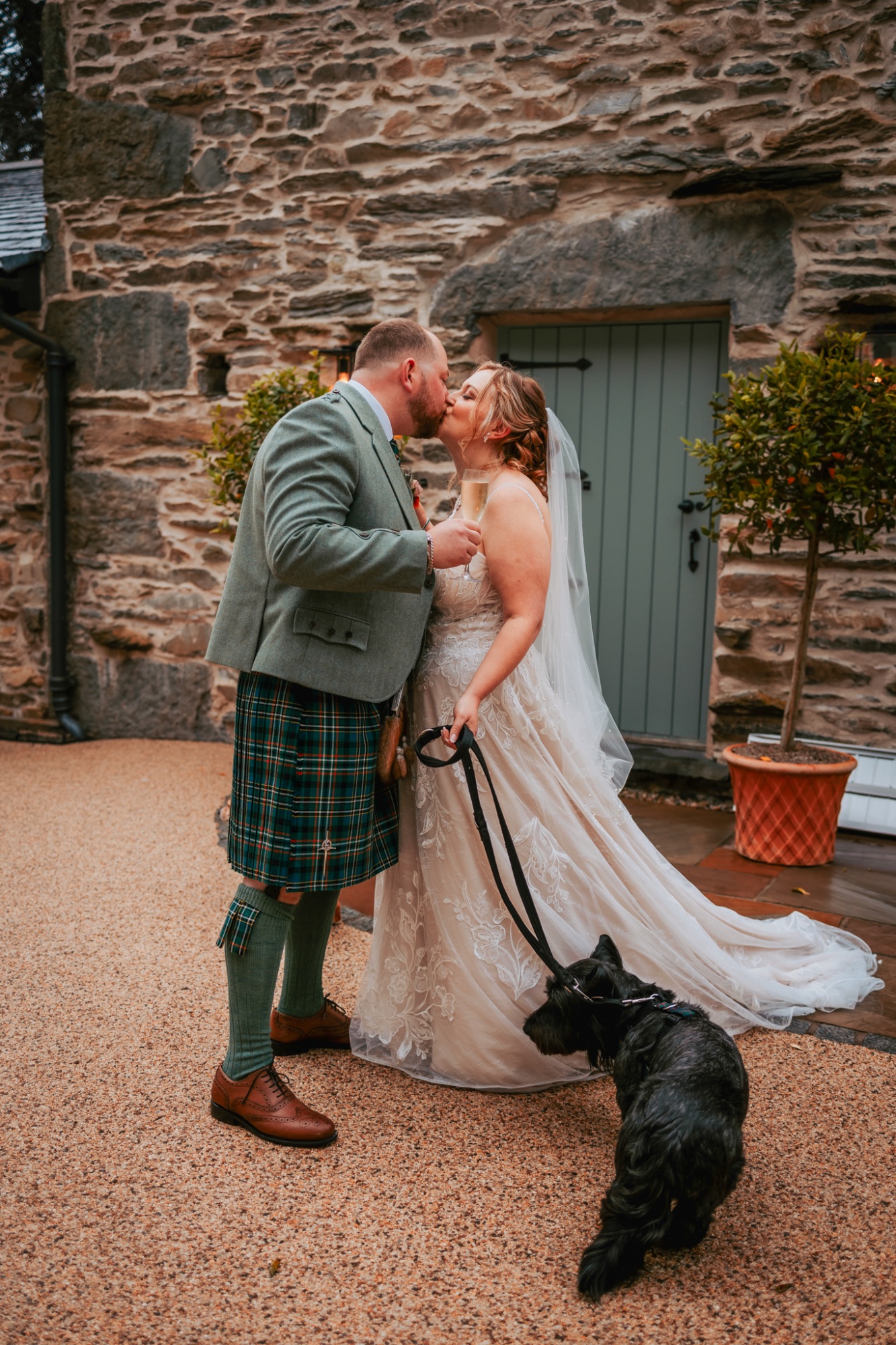 Bride and groom kiss after wedding ceremony with their dog with them