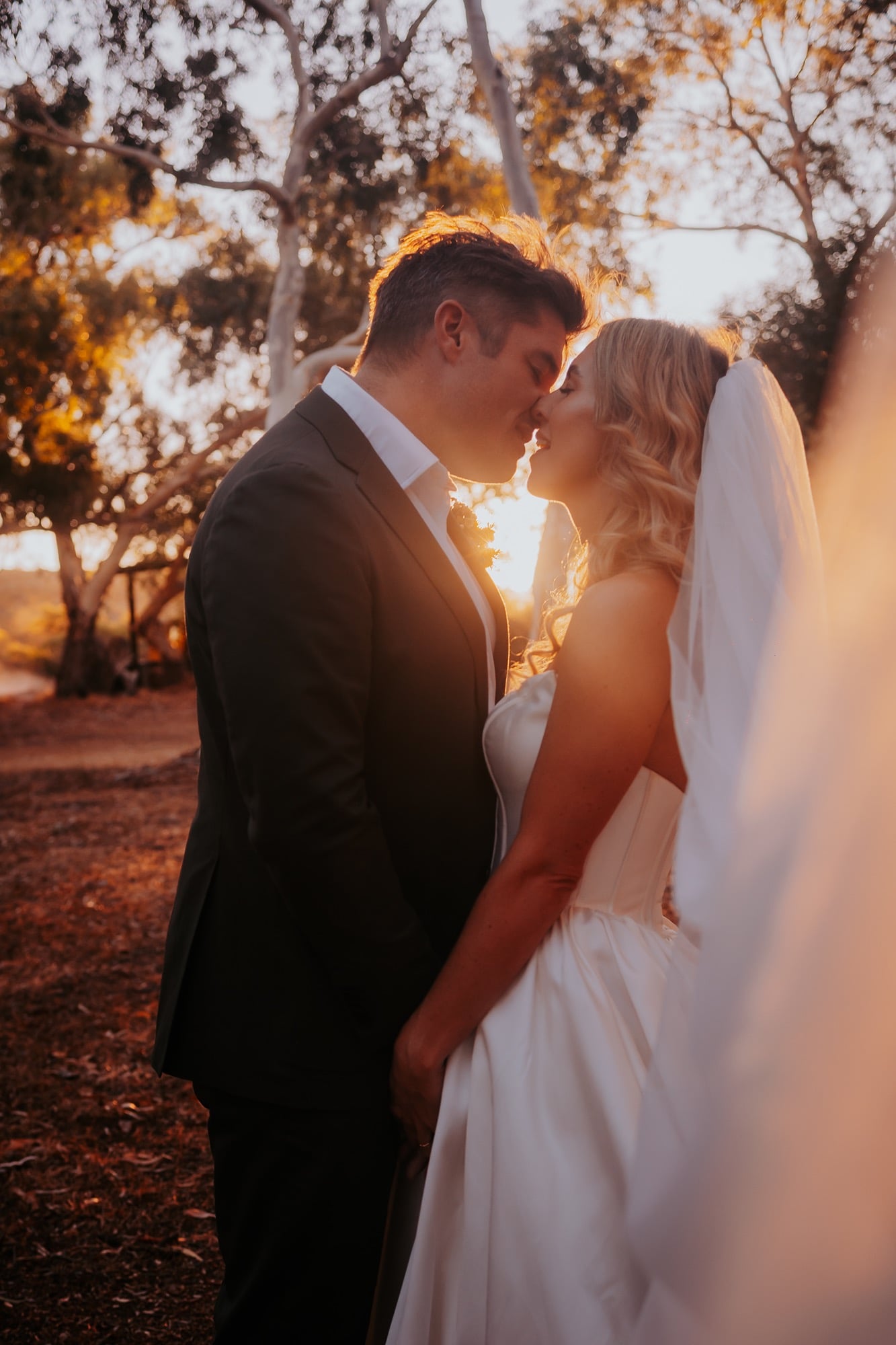 Bride and groom kiss at sunset, in the Australian outback