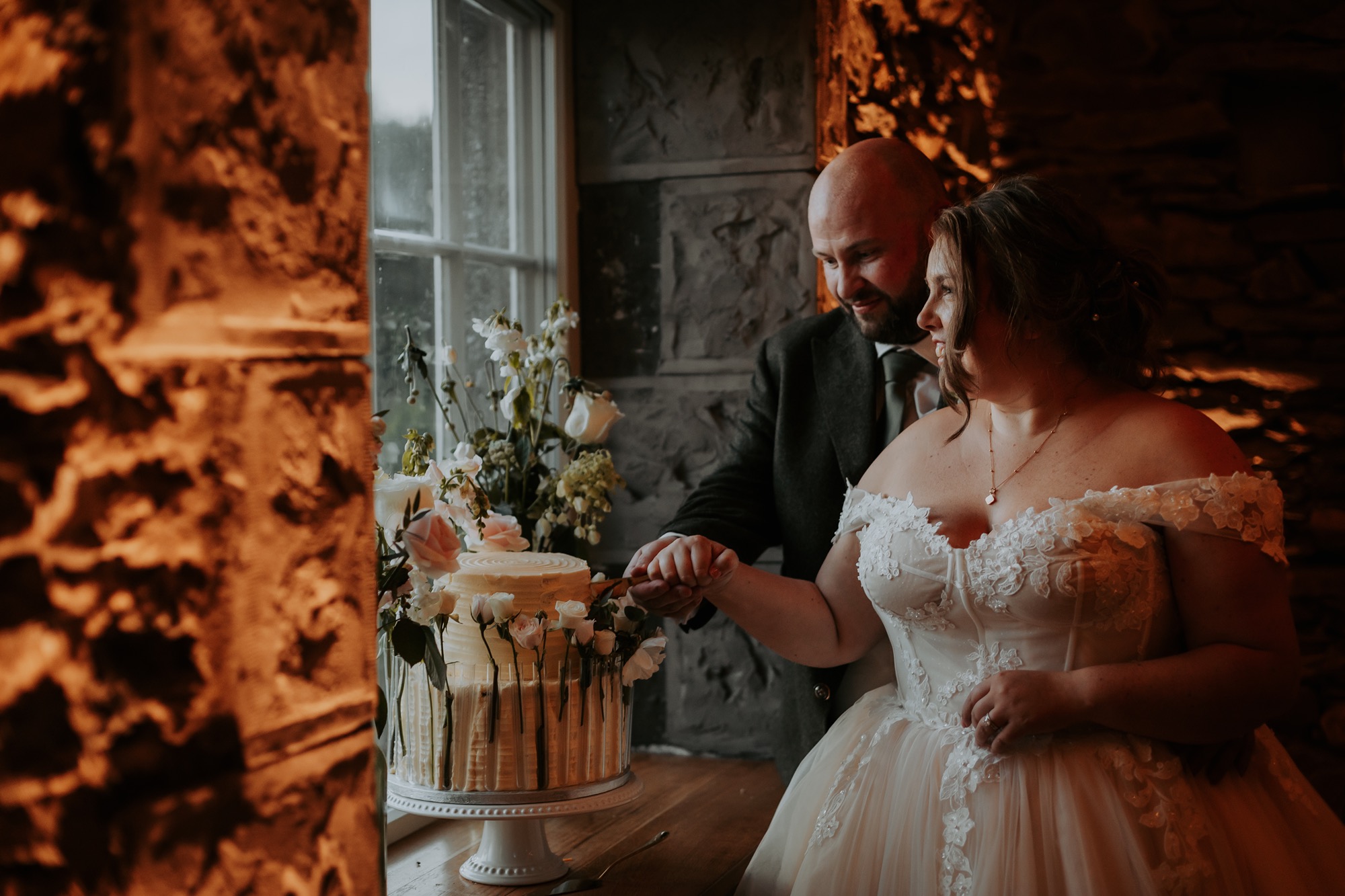 Bride and Groom cut wedding cake in Town Head Estate wedding barn, Windermere, Lake Disitrct