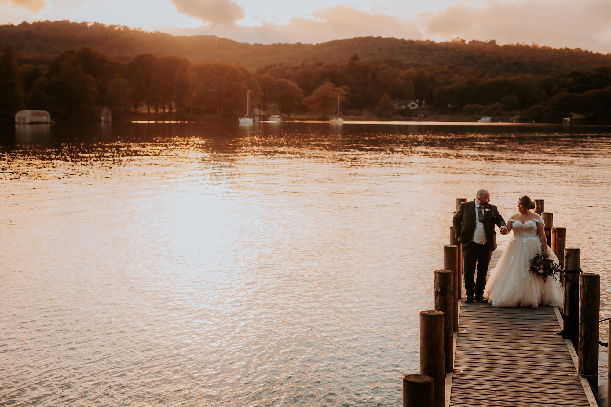 Bride and groom walk on private jetty at Town Head Estate, Windermere, Lake District