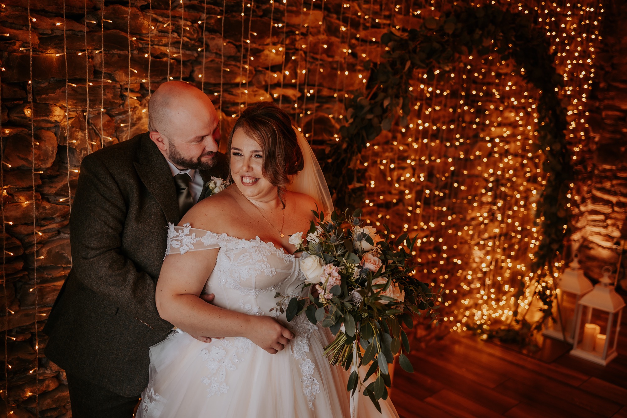 Bride and groom cuddle in the window light at Town Head Estate rustic wedding barn