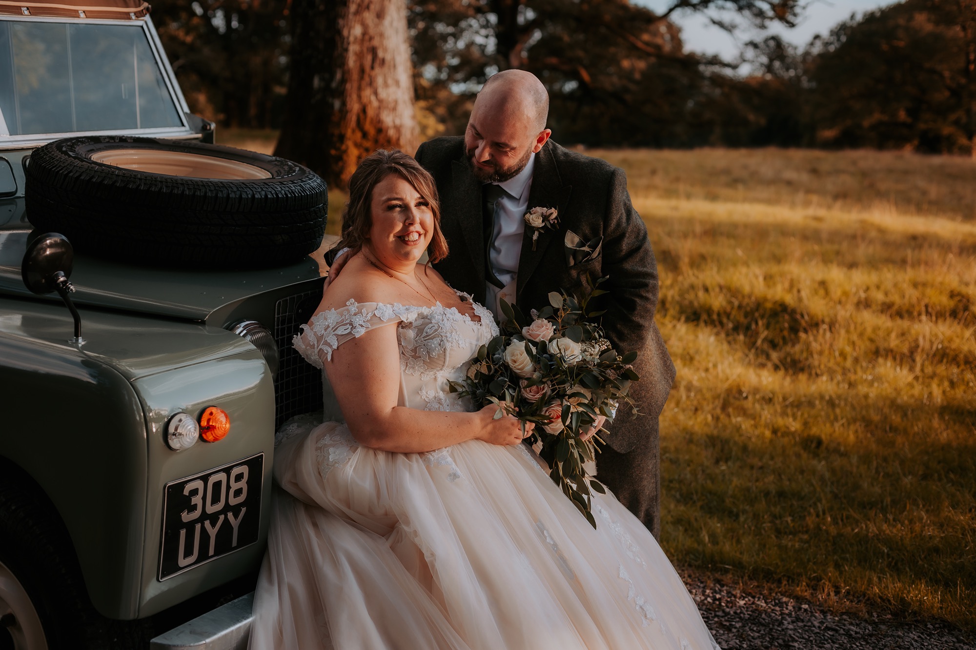 Bride and groom relaxed at front of vintage landrover