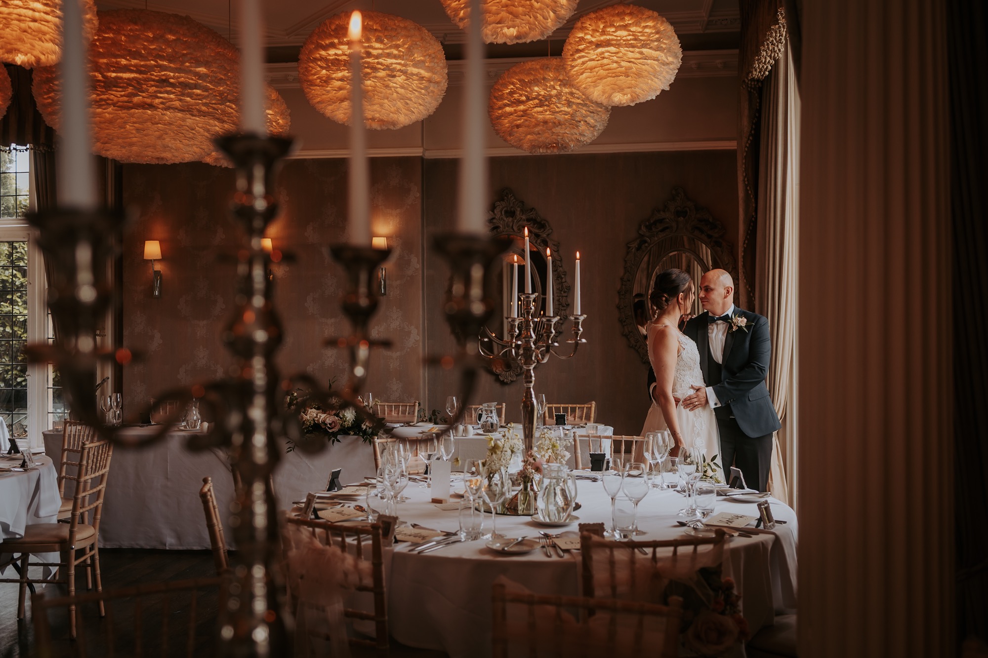 Bride and groom romancing near window within wedding breakfast set up at Falcon Manor, North Yorkshire wedding Venue