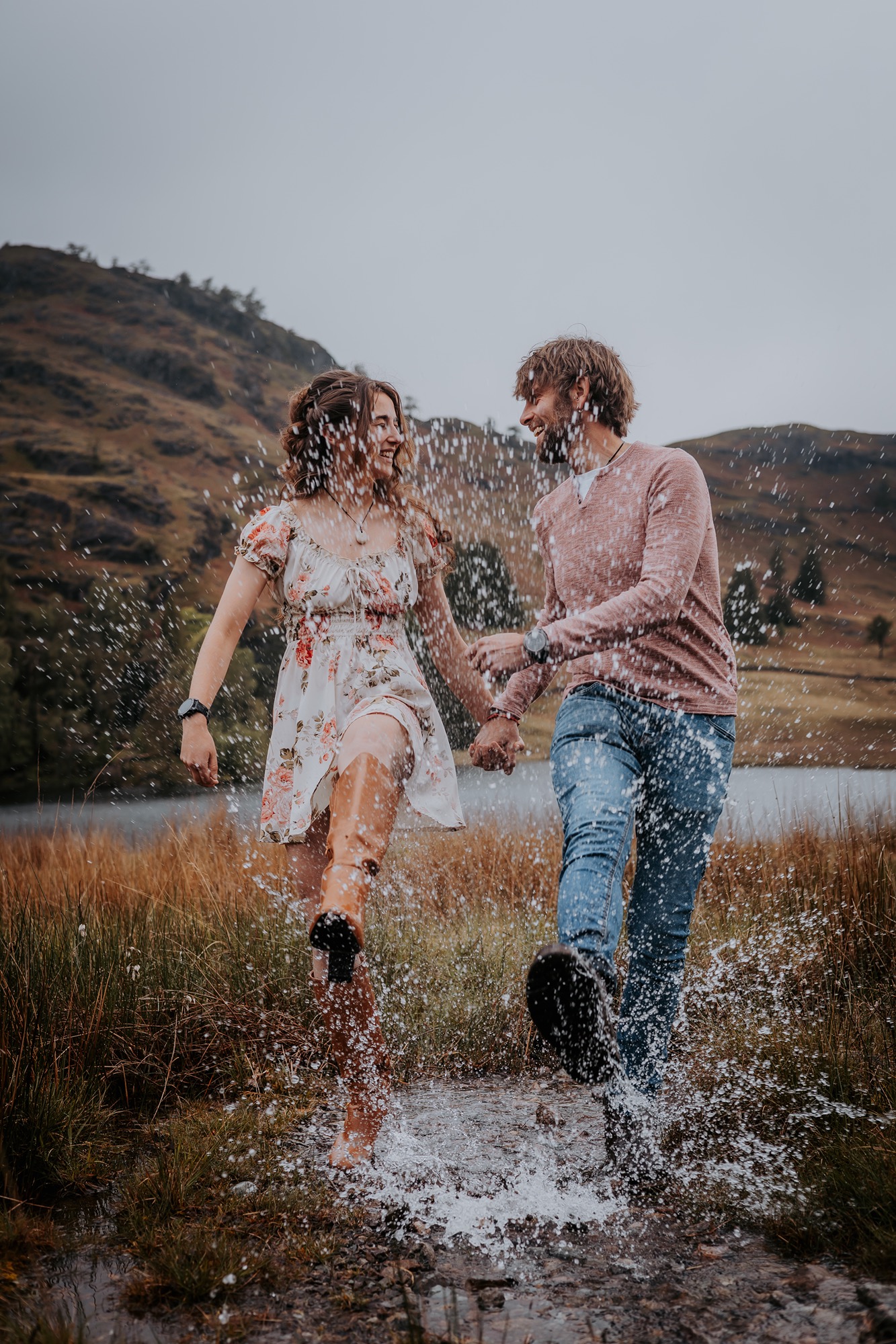 Couple splashing in puddle at Blea Tarn, Lake District ahead of their wedding