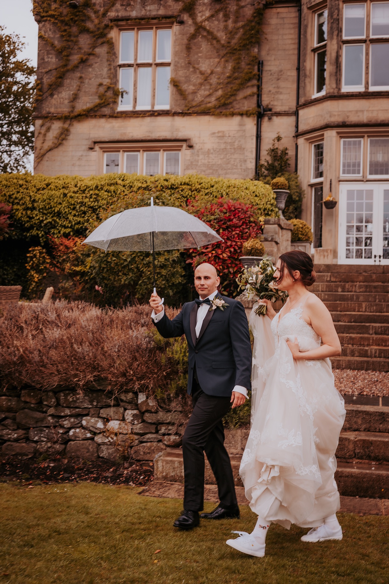 Couple walking out with umbrella at Falcon Manor, Setlle, North Yorkshire wedding venue