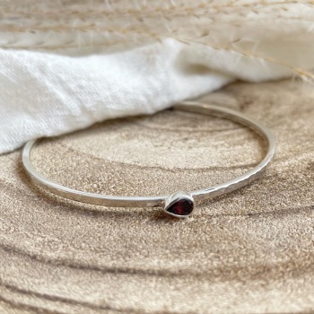 Bangle in hammered finish with pear shaped garnet