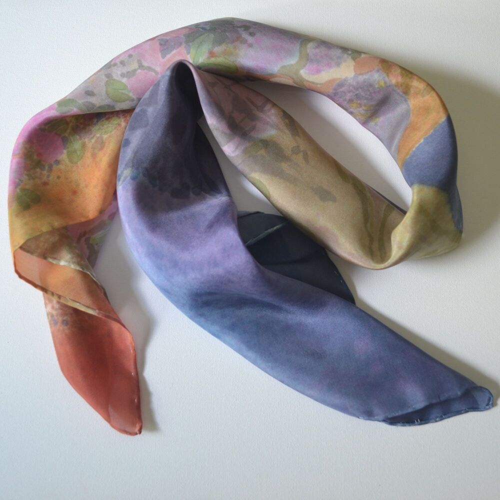 silk scarf in blues, pinks and rust colours rolled and folfed