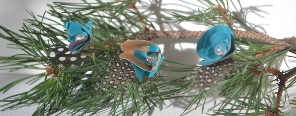 flower and feather decorations on a pine branch