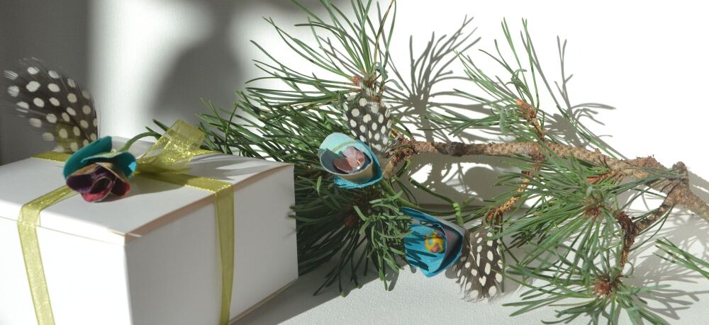 flower and feather decorations on a pine branch