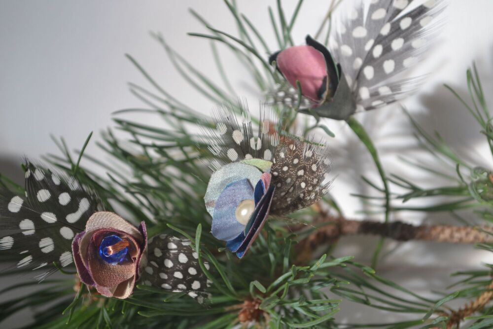 flower and feather decorations on a pine branch