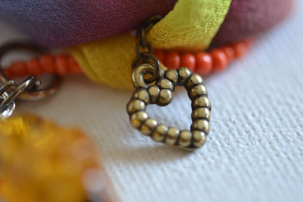 necklace detail with metal heart orange beads and silk