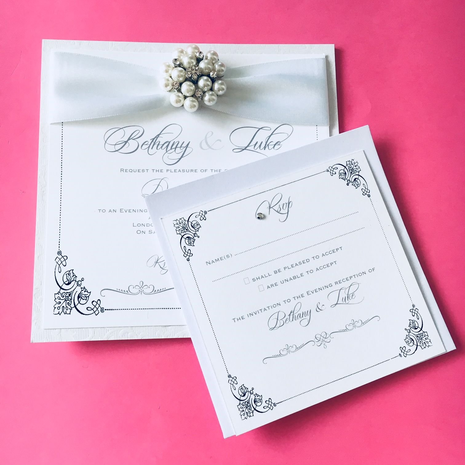 White postcard style invitation with Rsvp insert decorated with white ribbon, crystal pearl brooch 