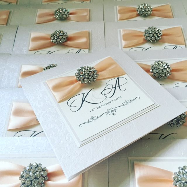 Monogram invitations with peach ribbon and diamante brooch
