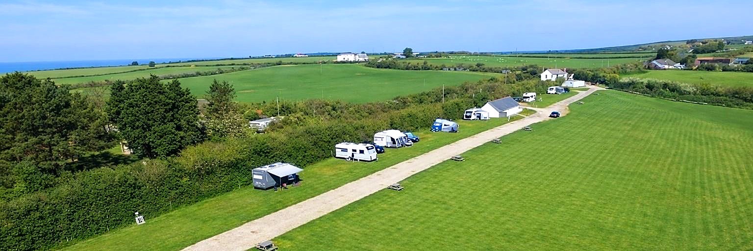 Arial view of Rosebud Farm Touring Park showing caravans, tents, motorhomes and campervans on pitches across the site